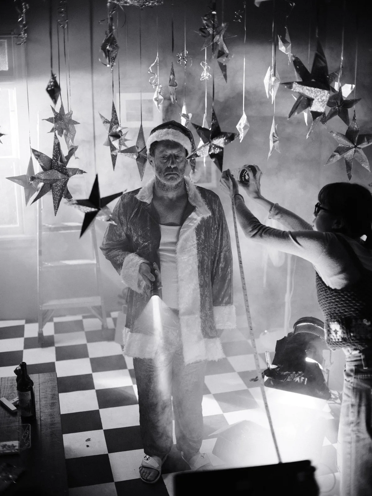 a costumed performer surrounded by hanging stars and production crew in black and white